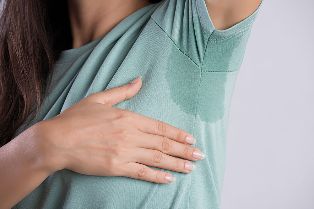 Close-up asian woman with hyperhidrosis sweating. Young asia woman with sweat stain on her clothes against grey background. Healthcare concept.