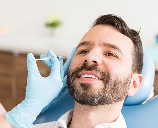 Closeup of mid adult man smiling while undergoing anti-aging treatment