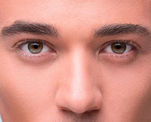 Everything should be perfect. Worried man with a stubble examining his nose and looking at camera while standing against grey background. Human face. Studio shot. Rhinoplasty