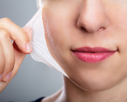 Portrait Of A Beautiful Young Woman Removing Peeling Mask From Her Face